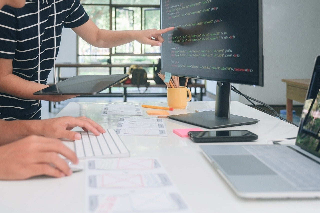 Sviluppatori web al lavoro su codice e bozze di un sito alla scrivania